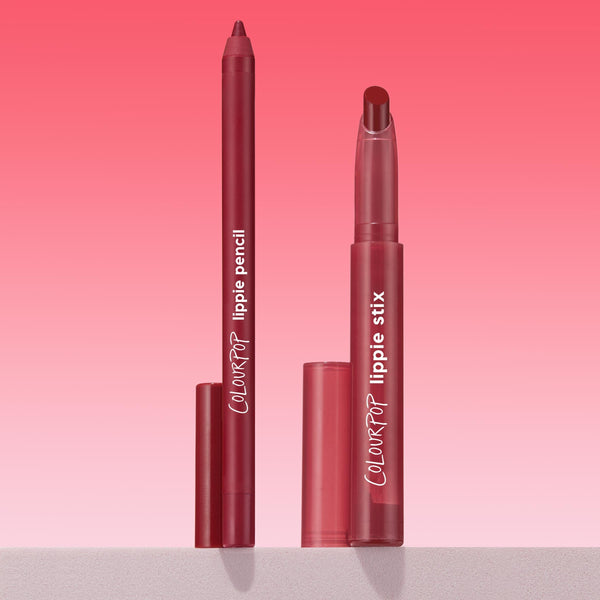 ColourPop Lippie Stix + Pencil Set, Read My Lips, featuring a deep berry lip pencil and matching twist-up lippie stix standing uncapped with caps beside them, tips exposed for application on a pink gradient backdrop.