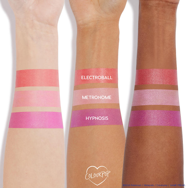 ColourPop Cream Blush Hypnosis swatched in a bold, cool fuchsia with a luminous sheen across three skin tones, positioned beneath coral Electroball and soft pink Metronome swatches on forearms against a white studio background.