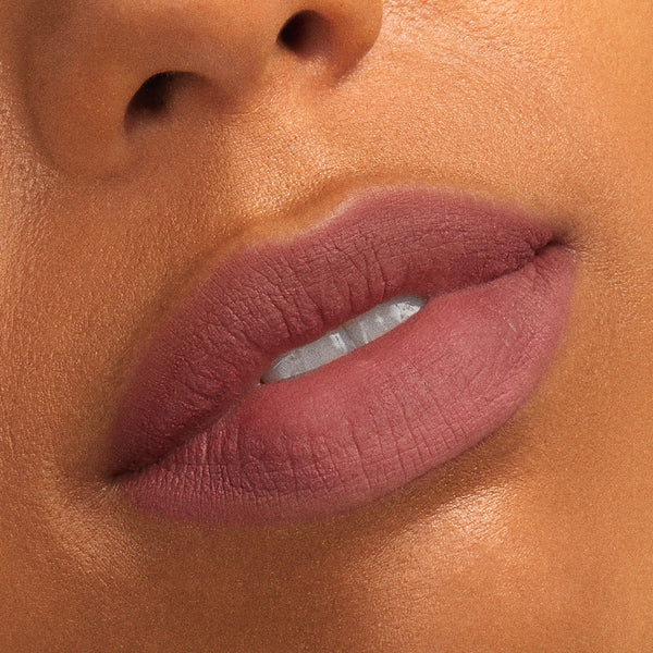 Rosy-mauve matte lips wearing That’s So Rosy, a lip swatch from the ColourPop Cheek & Lip Set, showing smooth full-coverage color on warm tan skin in a tight beauty close-up.