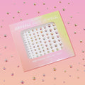 ColourPop Crystal Face Jewels Individual sheet displaying 81 adhesive iridescent rhinestones arranged by size, shimmering in a die-cut window, set against a pink gradient background with scattered crystals for a sparkly makeup look.