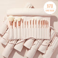 Sweet Fantasy ColourPop Shadow Palette & Brush Set brush roll opens to reveal soft white-bristle face and eye brushes with rose-gold ferrules, arranged in a blush-pink travel case on a textured nude surface, with a $70 ($140 value) badge.