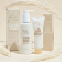Cloud Bank Milky Cleanser pump bottle by Fourth Ray Beauty stands beside its box, flanked by The Light Weight Hydrator on a beige set with pampas, showcasing a 5.8 fl oz ColourPop Face Cleanser with a 98% naturally derived formula.