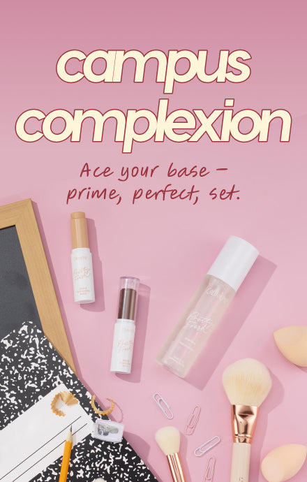senjyuan.onlineplexion essentials arranged in a flat lay - concealer, primer, and setting spray - paired with makeup brushes, paper clips, and a composition notebook on a pink background with the headline “campus complexion” for back‑to‑school.