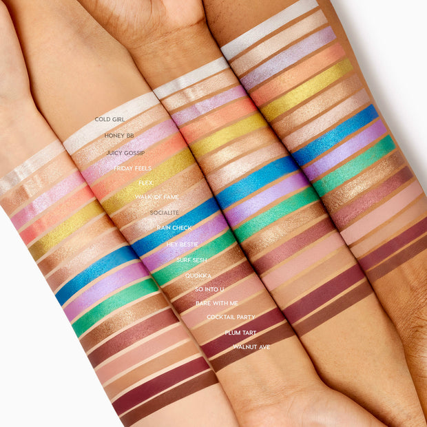 Friday Feels Shadow Stix swatch - one creamy, shimmery stripe - glides across multiple forearms of different skin tones, shown alongside the full ColourPop Shadow Stix lineup to demonstrate pigment payoff and blend in bright studio lighting.
