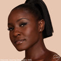 Deep Dark 210 C shade worn on a model’s face, showcasing smooth, dewy medium coverage with a warm undertone; ColourPop Hyaluronic Hydrating Foundation in a close-up studio portrait against a beige background with soft glam eye and glossy lips.