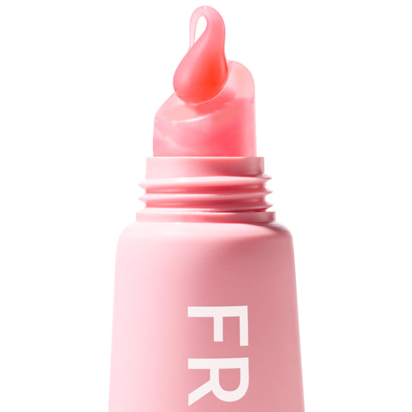 ColourPop Fresh Kiss Glossy Balm in Strawberry Milk forming a glossy milky-pink droplet on its slanted applicator as it emerges from a pastel pink squeeze tube, macro close-up on a clean white studio background.
