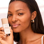 ColourPop SOL Liquid Sun Glow Drops in Bronze Glow held beside a model’s face, showcasing a dewy bronze finish; white bottle with rose-gold cap and label noting niacinamide + peptides, 1 fl oz, in soft studio lighting.