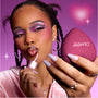 Model applies shimmery pink gloss while holding a heart-shaped senjyuan.onlinepact, showing bold purple and pink heart eye makeup that highlights the Heart to Get Full Collection full collection set against a dreamy pink background.