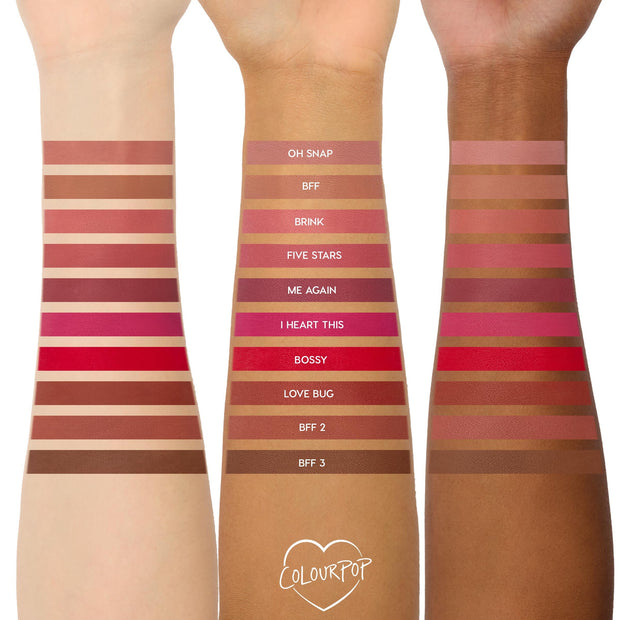 Three arms in light, medium, and deep skin tones display swatches of The Lil Box of Lippie Pencils lip liner shades from Colourpop, arranged in horizontal strips labeled from nude mauves to bright reds and warm browns for comparison.