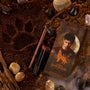 ColourPop Power Pout Lipstick, Bella! Where the Hell Have You Been, Loca?, resting with a matching brown lip pencil and themed box on earthy soil amid stones and driftwood, featuring a wolf paw print and moonlit wolf graphic evoking Twilight New Moon.