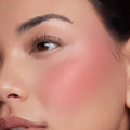 IKTR ColourPop Liquid Blush creating a dewy rosy-pink flush on a model’s cheek, seamlessly blended from the apples to the cheekbone in a tight close-up under natural light, highlighting the liquid formula’s smooth, buildable finish.