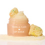 Vanilla Cake ColourPop Lip Scrub jar sits open, sugary scrub mounded on top and swatched at the base, flanked by funfetti cake crumbs on a clean white studio background.