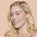 Fair 07 C shade brightening a model’s complexion with smooth, dewy medium coverage from the ColourPop Pretty Fresh Creamy Concealer, shown in a close-up against a peach backdrop to showcase even tone around eyes and cheeks.
