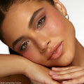 Model showcasing Coconut BB shadow palette set by Colourpop, resting her face on her hands while wearing warm neutral eye shadow and blush from the Value Sets collection against a clean white studio background.