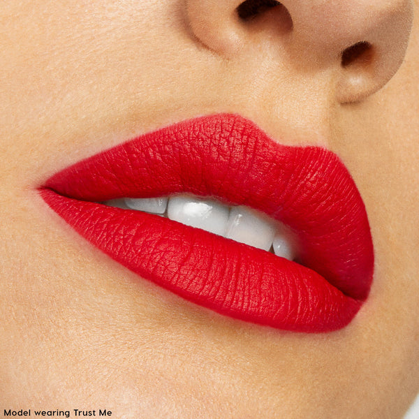 Close-up of matte red lips wearing ColourPop Lippie Stix in Trust Me, lips slightly parted to show smooth, opaque color with crisp edges, photographed in studio as a shade swatch for The Lil Box of Lippie Stix.
