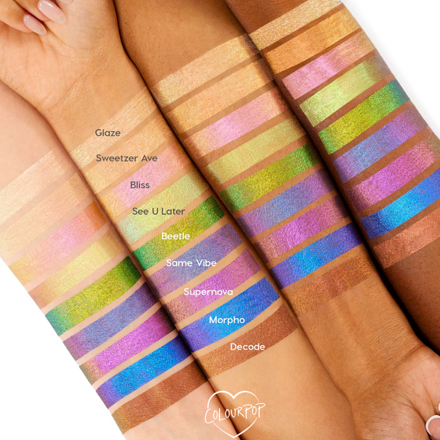 Bliss Chrome Liquid Shadow swatch flashes pink to gold on several skin tones, lined alongside other labeled shades across forearms, showcasing the prismatic, long‑wear finish of ColourPop Chrome Liquid Shadow.