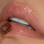 Glossy nude lips receive a swipe of honey-colored lip mask with a spatula, highlighting hydration and shine from the Sweet as Hunny Eye & Lip Set in the ColourPop Lip Care Kit, macro close-up of lips and applicator.