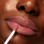 Doe-foot applicator swipes a dusty-rose tint onto softly matte lips, showcasing Mood 24/7 from the ColourPop Cheek & Lip Set in a tight beauty close-up that highlights smooth texture and precise application.