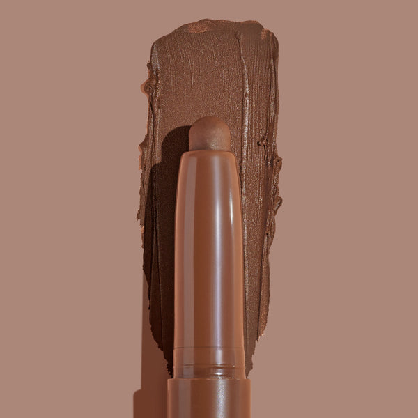 Walnut Ave ColourPop Shadow Stix sweeping a thick, matte walnut-brown swatch on a taupe background, showing the twist-up cream eyeshadow pencil tip and rich pigment payoff for easy, on-the-go eye color.