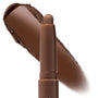 ColourPop Shadow Stix in Walnut Ave stands uncapped, showing a rounded tip while a broad swatch behind reveals a rich warm walnut-brown pigment; creamy, blendable eyeshadow stick on a clean white background.